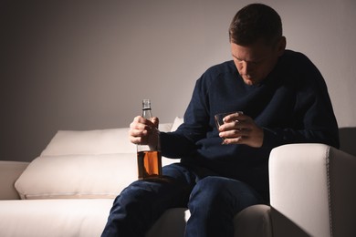 Addicted man with alcoholic drink on sofa indoors
