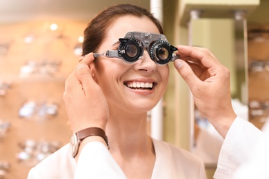 Woman having eye examination with phoropter in optical store. Ophthalmologist prescription