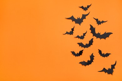 Paper bats and space for text on orange background, flat lay. Halloween decor