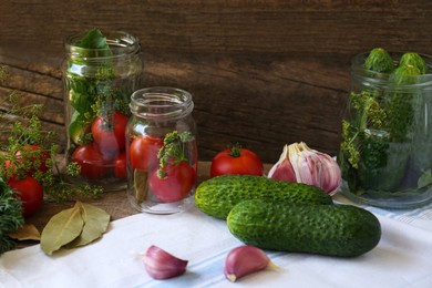 Photo of Glass jars, fresh vegetables and herbs on wooden table. Pickling recipe