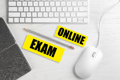 Flat lay composition with mouse, keyboard and phrase ONLINE EXAM on white wooden table