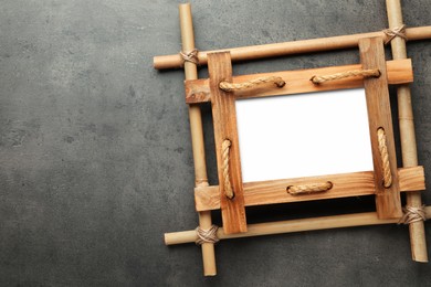 Empty bamboo frame on grey table, top view. Space for text