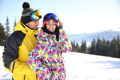 Photo of Young couple at ski resort, space for text. Winter vacation