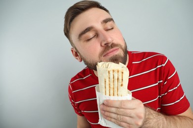 Photo of Young man with delicious shawarma on grey background, space for text
