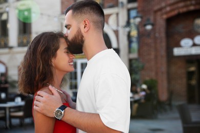 Handsome young man kissing his beautiful girlfriend on city street
