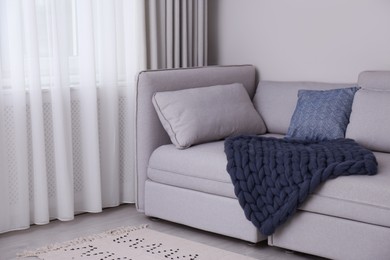 Living room interior with knitted merino wool blanket on sofa