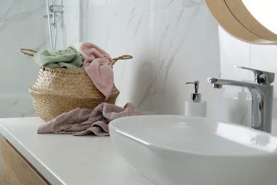 Wicker laundry basket with towels near sink on countertop in bathroom