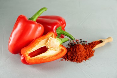 Fresh bell peppers and scoop of paprika powder on white table