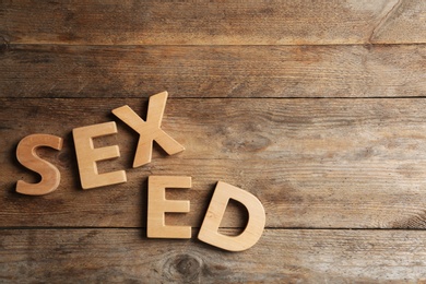 Phrase "SEX ED" made of different letters on wooden background, flat lay
