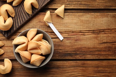 Photo of Tasty fortune cookies and paper with prediction on wooden table, flat lay. Space for text