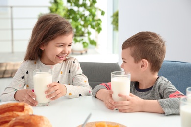Cute little kids having breakfast with milk at table