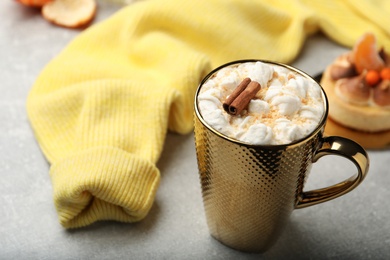 Photo of Delicious marshmallow drink and yellow sweater on light grey table