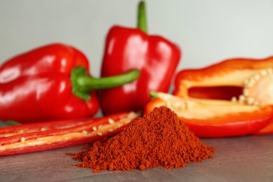 Fresh chili and bell peppers with paprika powder on grey table, closeup
