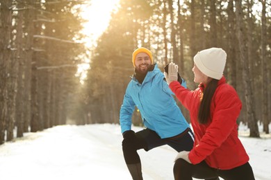 Happy people doing sports exercises in winter forest