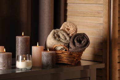 Photo of Spa composition with burning candles and rolled towels on table in wellness center