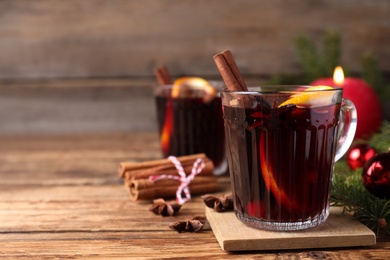 Aromatic mulled wine on wooden table, space for text