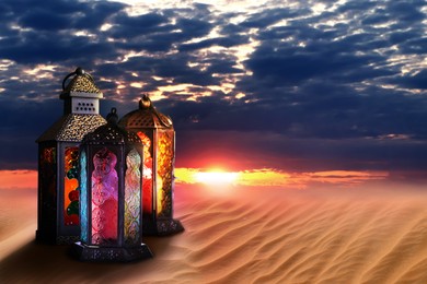 Beautiful Arabic lanterns on sand at sunset, space for text