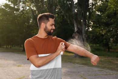 Man applying insect repellent on arm in park. Tick bites prevention