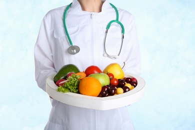 Female doctor with fresh products on light background. Cardiac diet