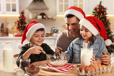 Photo of Happy father and his children making dough for delicious Christmas cookies at home