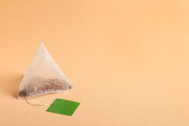 Paper tea bag with tag on beige background, space for text