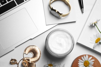 Flat lay composition with jar of hand cream and chamomiles on white table