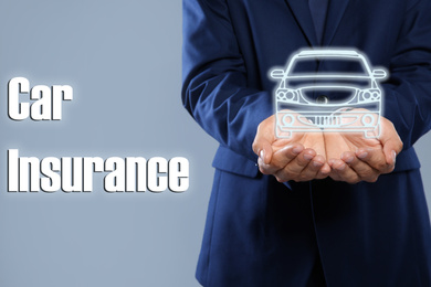 Man demonstrating image of auto on grey background, closeup. Car insurance