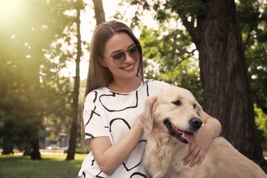 Photo of Young woman with her golden retriever dog in park