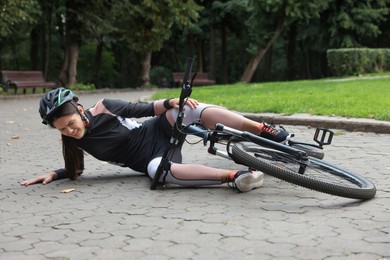 Young woman fallen off her bicycle in park