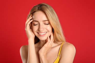 Portrait of beautiful young woman with blond hair on red background