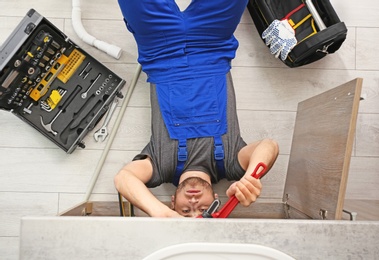 Professional plumber with set of tools working indoors, top view