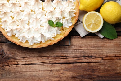 Flat lay composition with delicious lemon meringue pie on wooden table. Space for text
