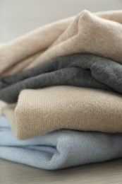 Photo of Stack of cashmere clothes on wooden table, closeup