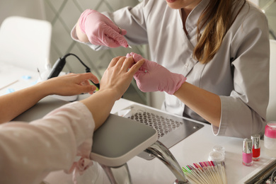 Professional manicurist working with client in beauty salon, closeup