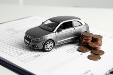 Toy car, money and insurance contract on table