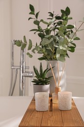 White bathtub with stylish decor and houseplants in bathroom. Interior design