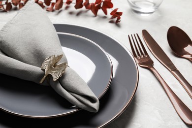 Photo of Plates with fabric napkin, decorative ring and cutlery on light gray marble table