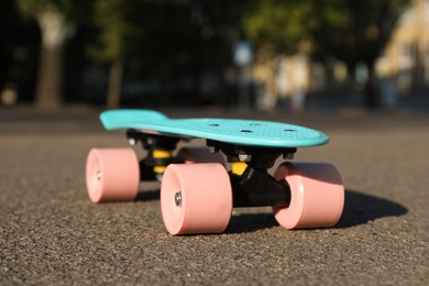 Light blue skateboard with pink wheels on asphalt outdoors