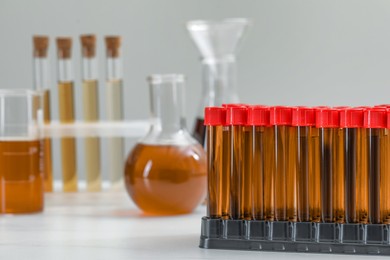 Photo of Different laboratory glassware with brown liquids on white table. Space for text