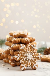 Tasty Christmas cookies on white marble table against blurred festive lights