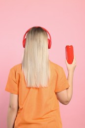 Photo of Woman holding red beverage can on pink background, back view