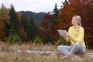 Photo of Young woman drawing with graphic tablet in mountains on autumn day