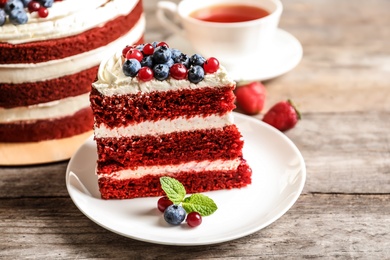 Plate with piece of delicious homemade red velvet cake on wooden table