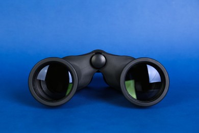 Modern binoculars on blue background. Optical instrument