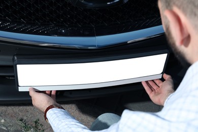 Man installing vehicle registration plate outdoors, closeup