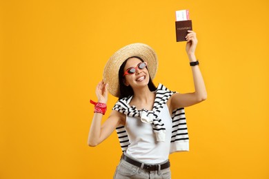 Happy female tourist with ticket and passport on yellow background