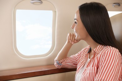 Young woman looking out window in airplane during flight