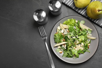 Tasty salad with pear slices served on black table, flat lay. Space for text
