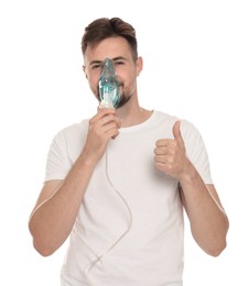 Man using nebulizer for inhalation and showing thumb up on white background