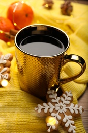 Photo of Cup of hot drink with yellow sweater and gingerbread cookie on table, closeup